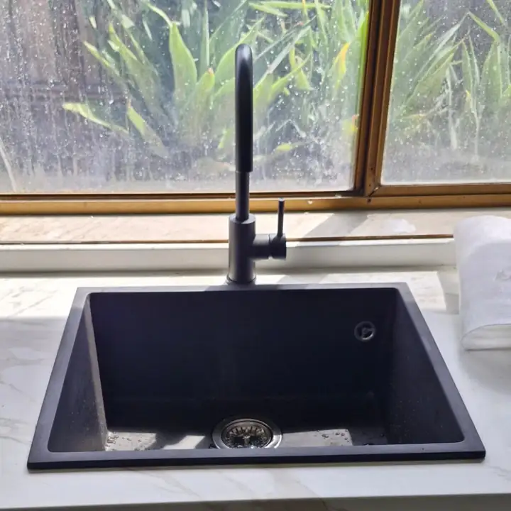 A black mixer tap over a black undermount kitchen sink